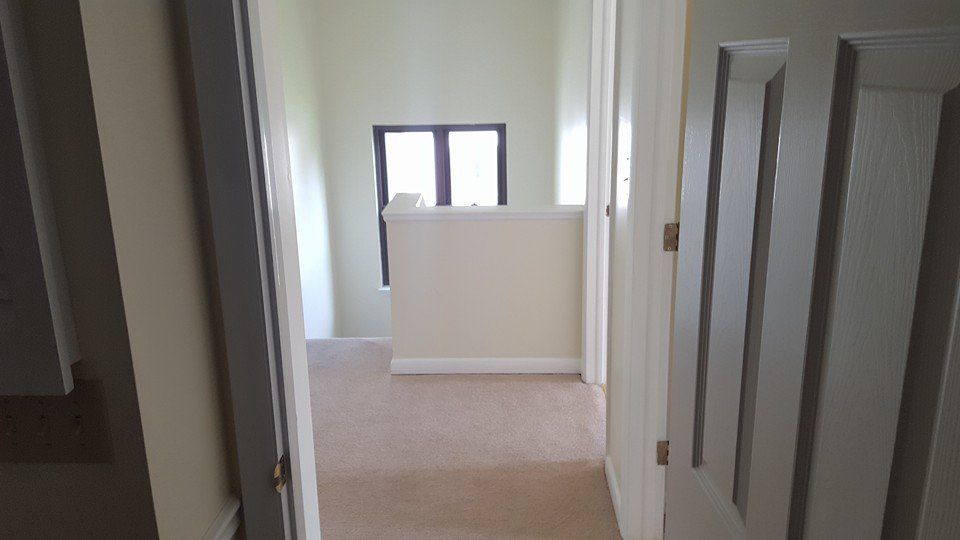 A hallway in a house with a window and a staircase.