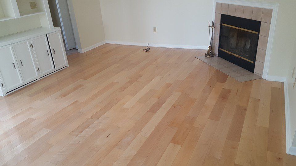 An empty living room with hardwood floors and a fireplace.