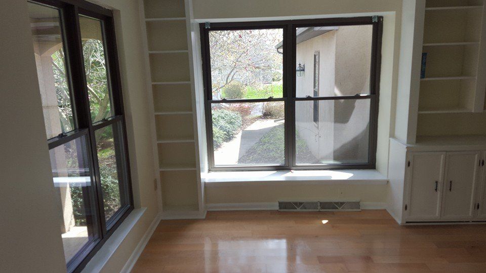 An empty living room with hardwood floors and a large window.