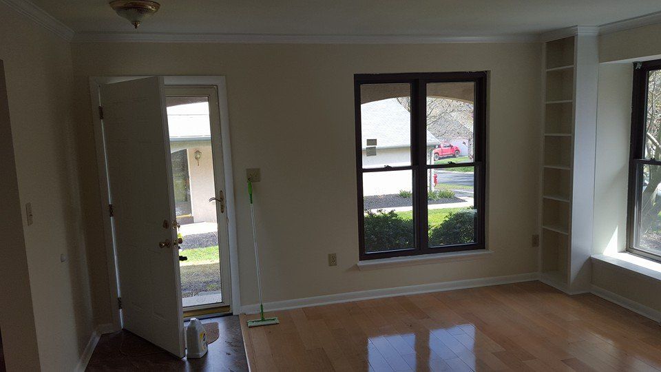 An empty living room with hardwood floors and two windows.