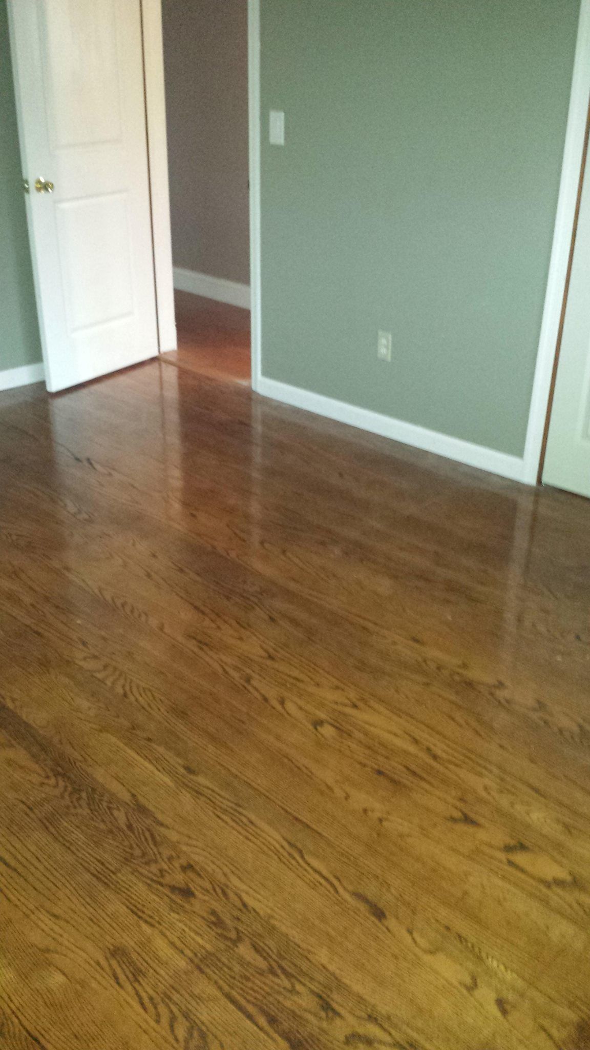A bedroom with hardwood floors and a doorway leading to a hallway.