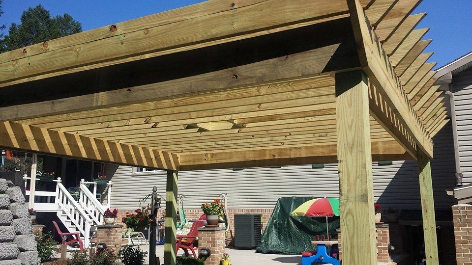 A wooden pergola is sitting in the backyard of a house.