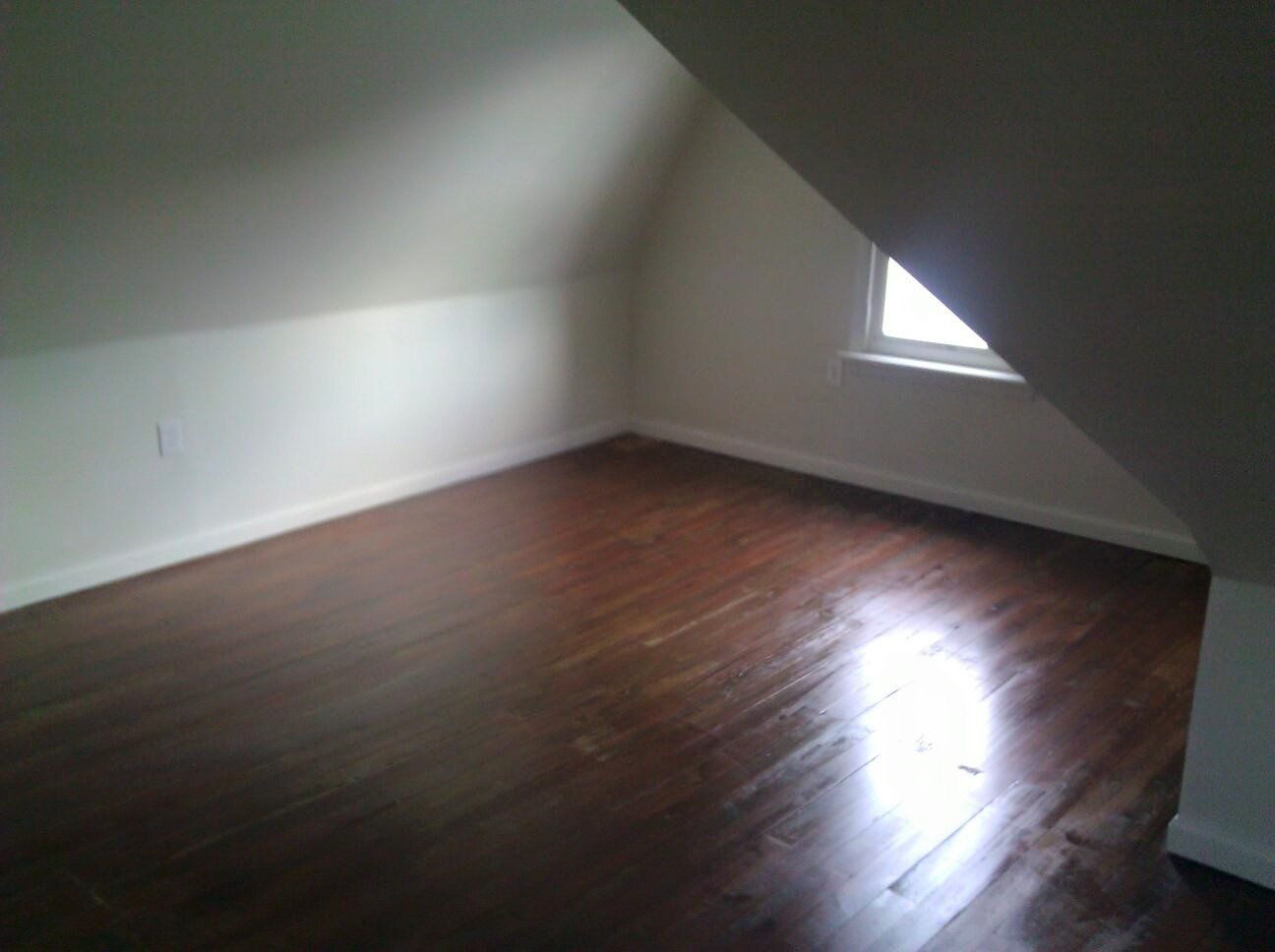 An empty room with hardwood floors and a window