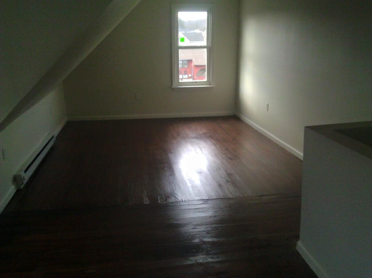 An empty living room with hardwood floors and a window.
