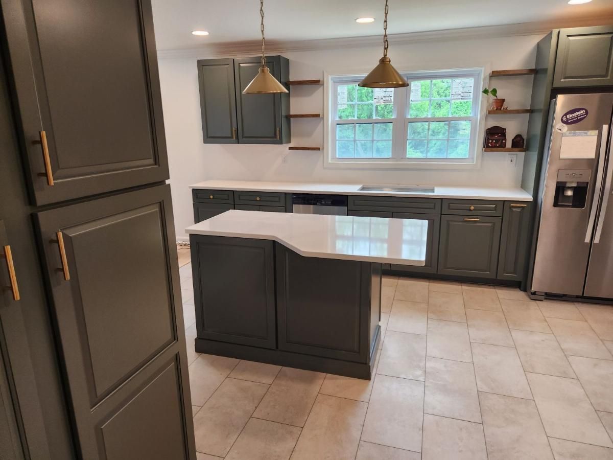 A kitchen with gray cabinets and a stainless steel refrigerator.