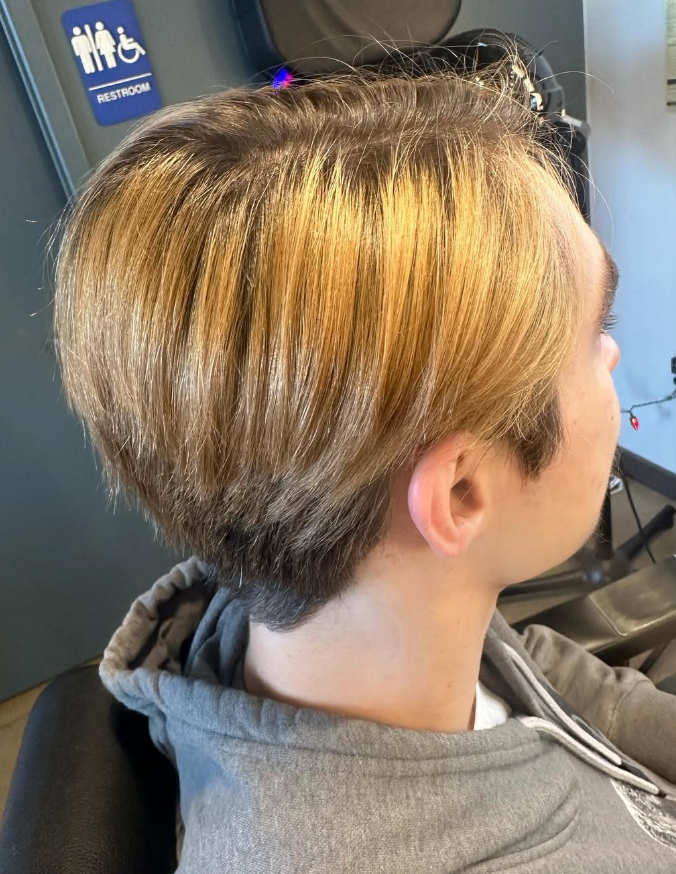 Person with short, layered blonde hair, viewed from the side, possibly in a salon.