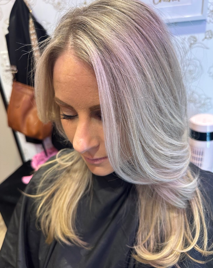 Woman with layered, ash blonde hair with a hint of purple highlights.