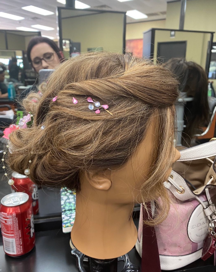 Mannequin head with brown hair in a formal updo, with pink and silver hair accessories.