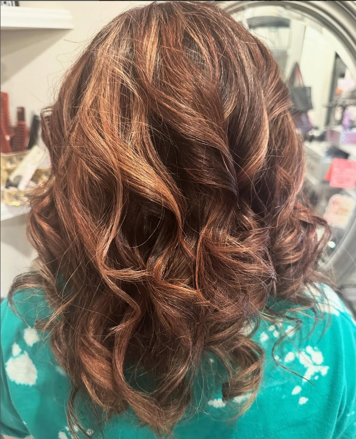 Woman's wavy, highlighted auburn hair.