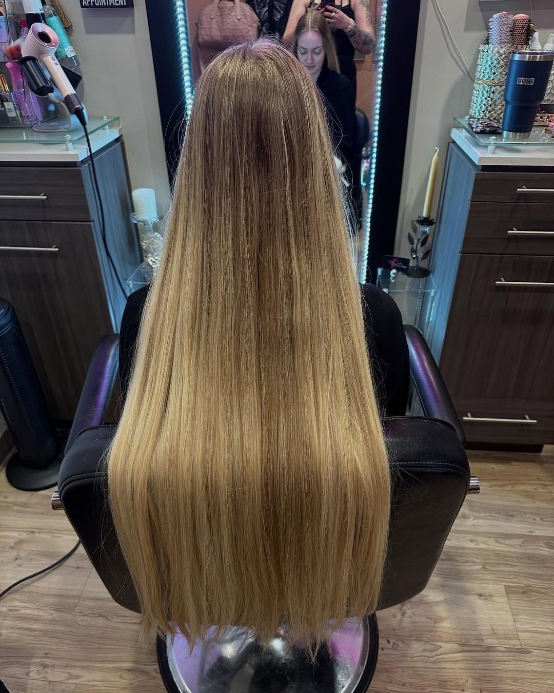 Woman with long, blonde, straight hair sitting in a salon chair.