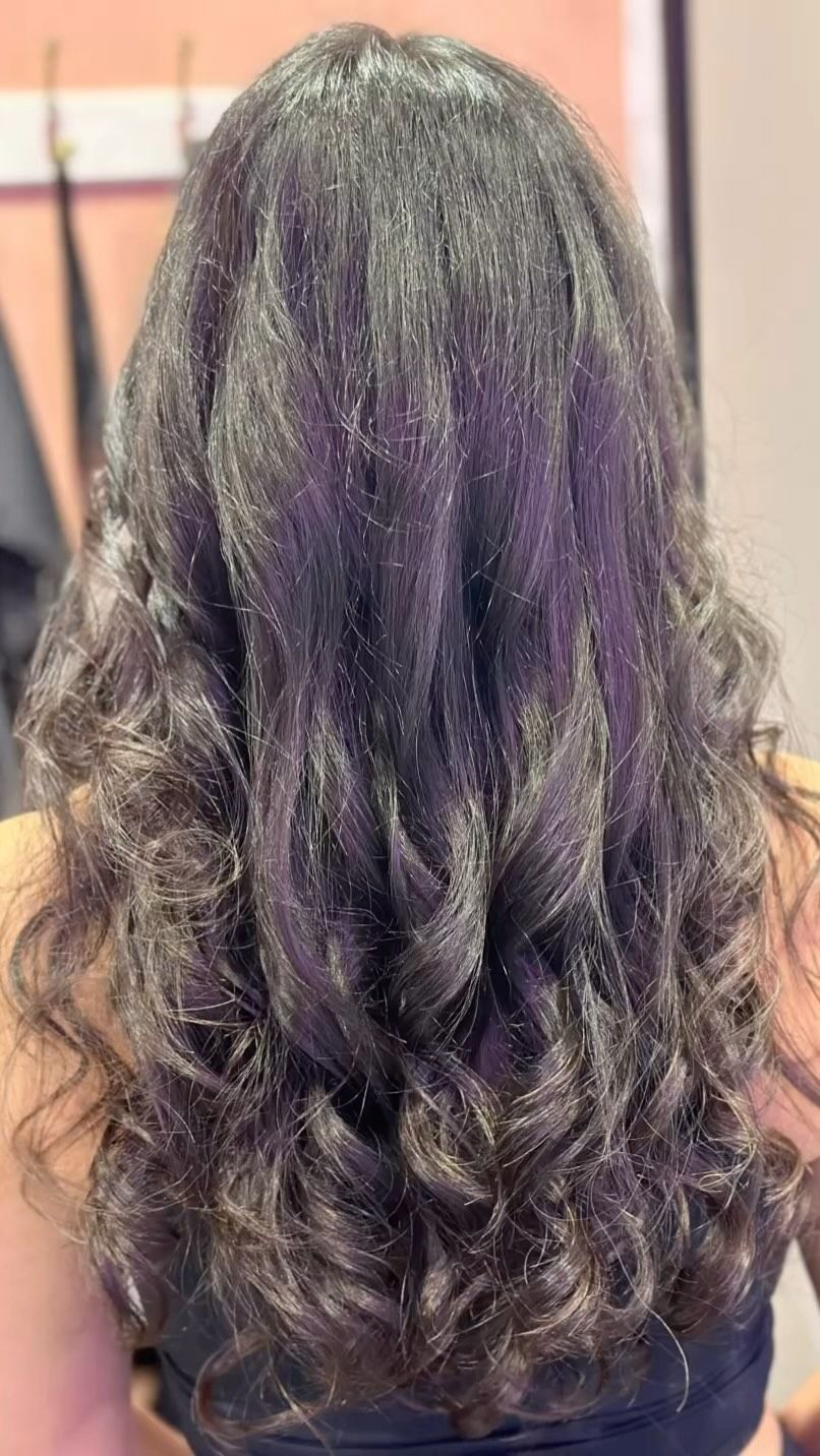 Long, wavy, dark brown hair. Back view of a person with styled curls.