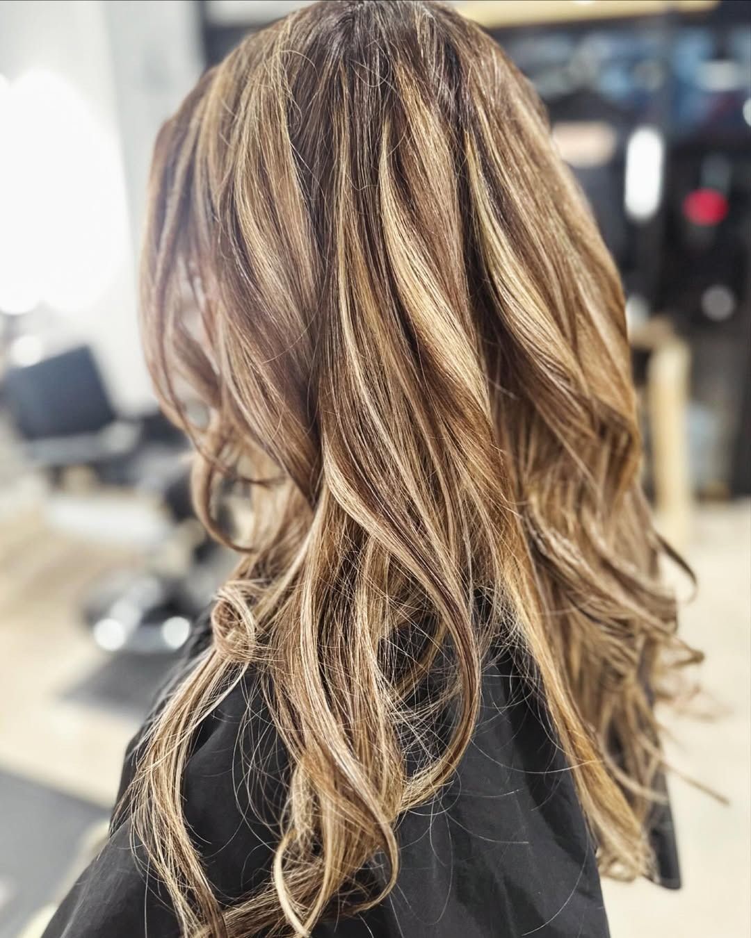 Long wavy brown hair with blonde highlights.
