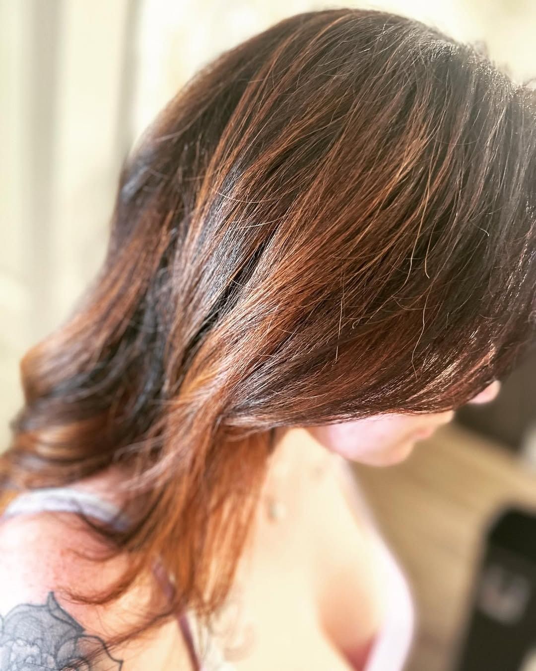 Woman with long, wavy brown hair with reddish highlights.