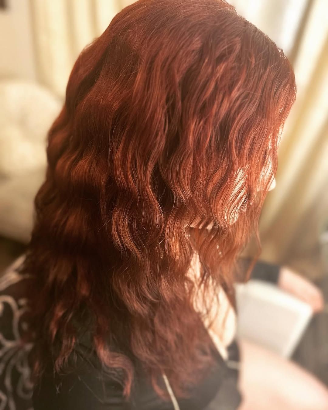 Woman with long, wavy, red hair; soft lighting.