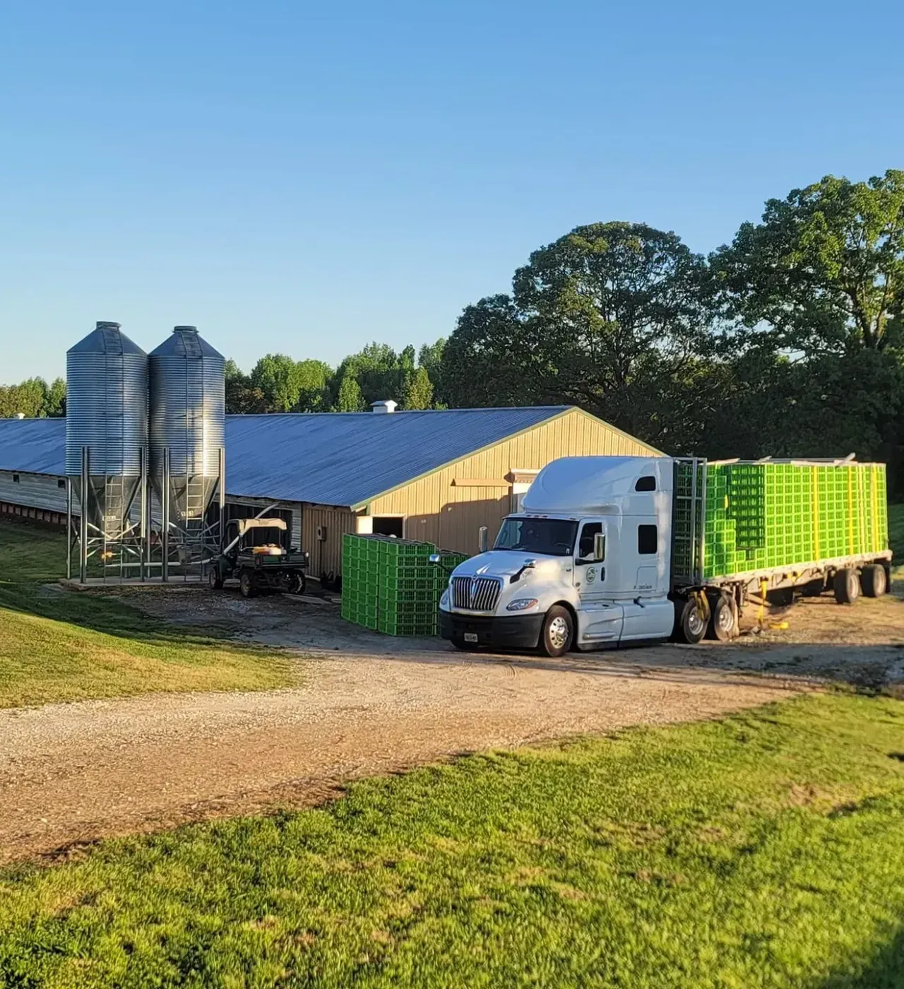 A semi truck is parked in front of a building on a dirt road.