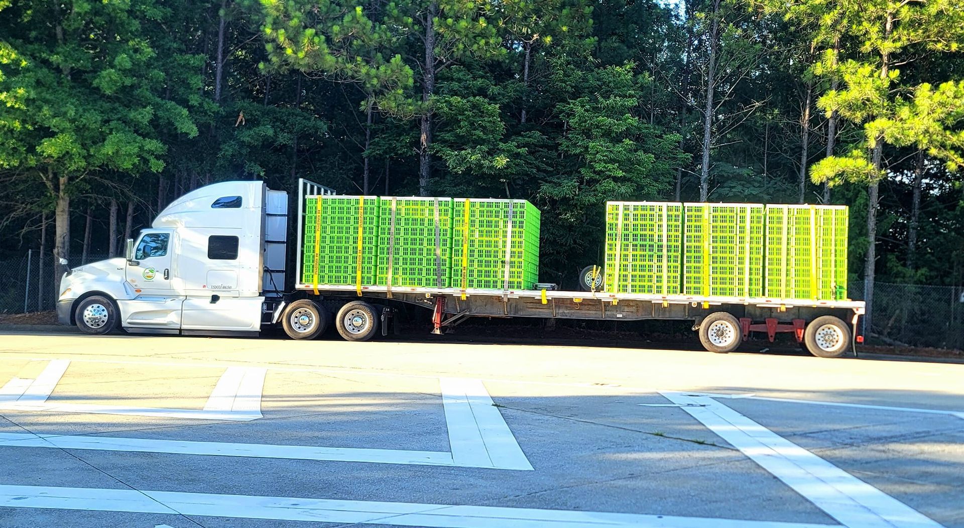 A semi truck is driving down a road with a trailer full of green crates.