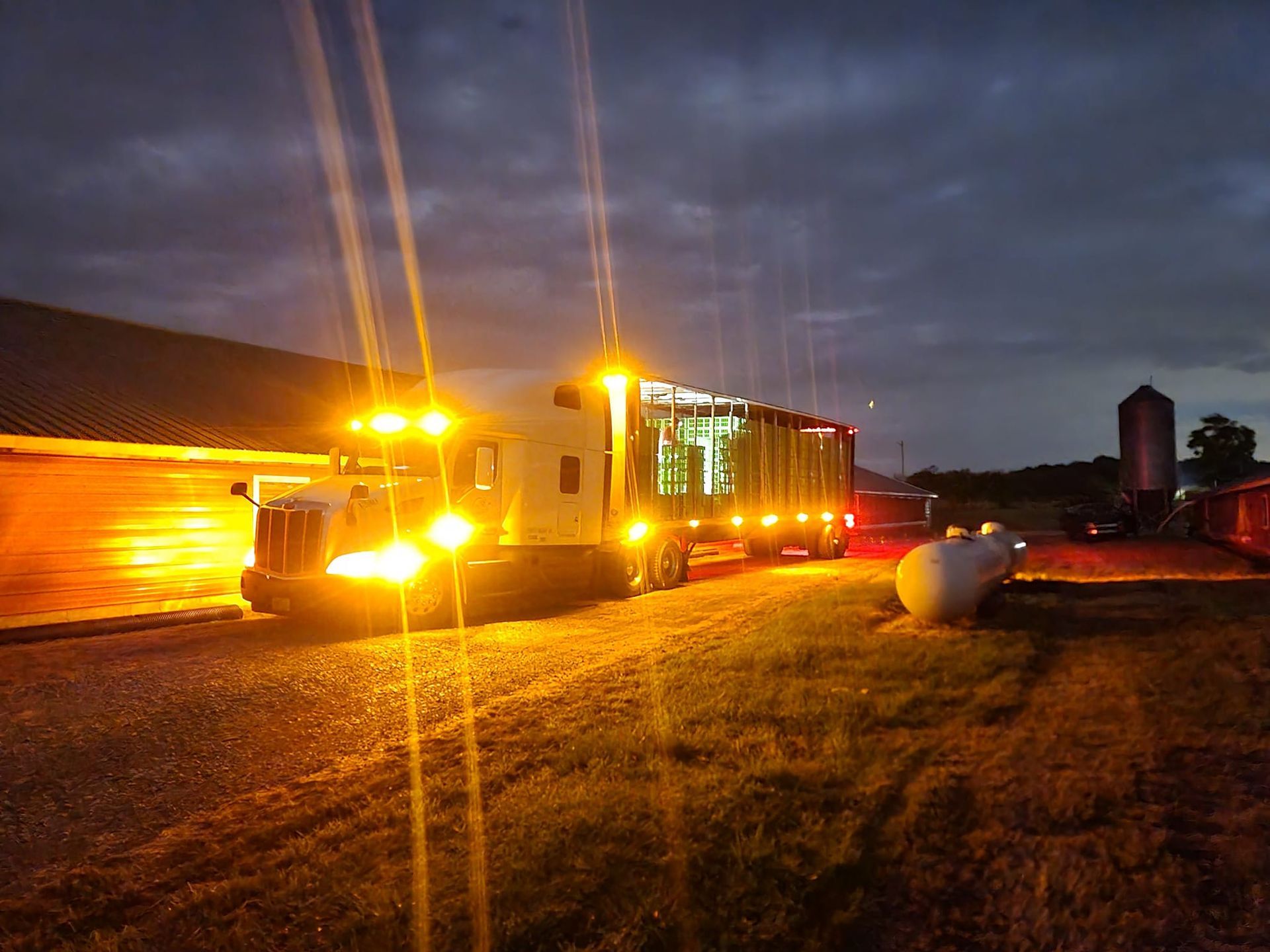 A truck is parked in front of a barn at night.