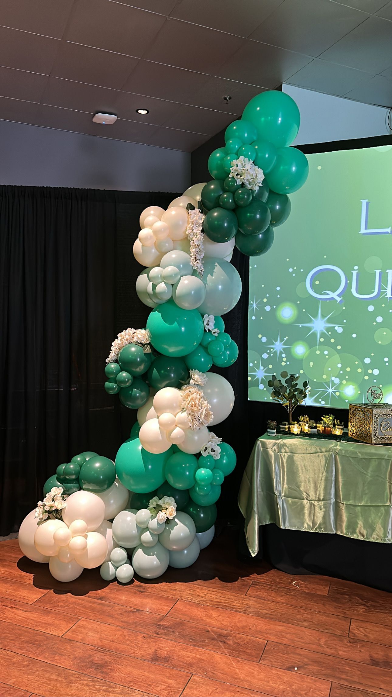 A room filled with green and white balloons and a table.