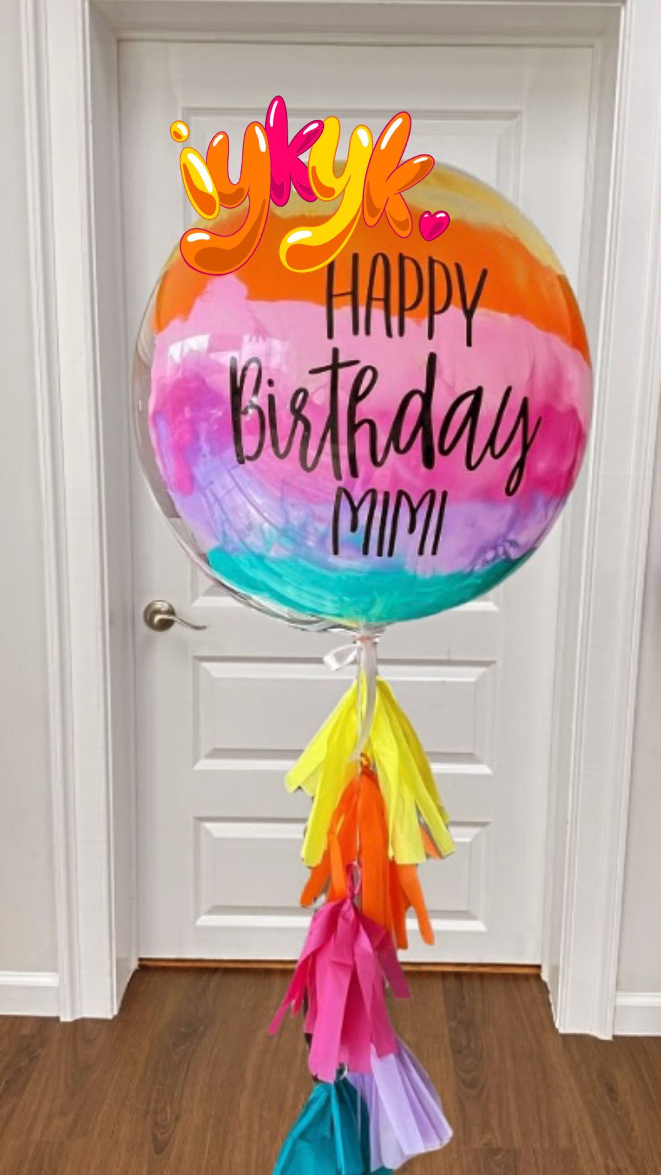 A colorful birthday balloon is sitting in front of a door.