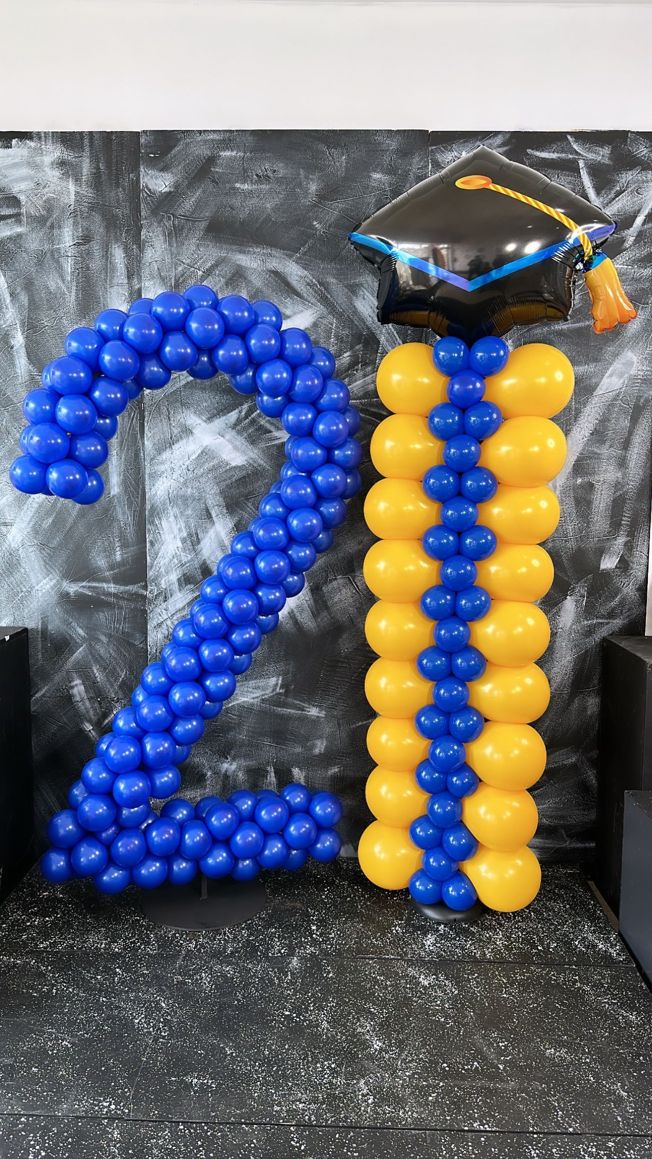 The number 21 is made out of blue and yellow balloons.