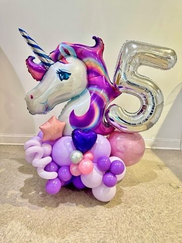 A unicorn balloon is surrounded by balloons and a number 5 balloon.