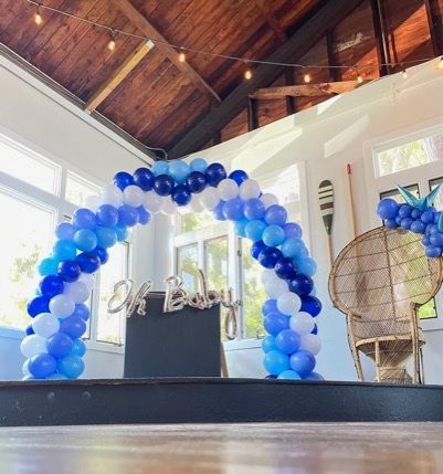 A room decorated with blue and white balloons and a sign that says ok baby