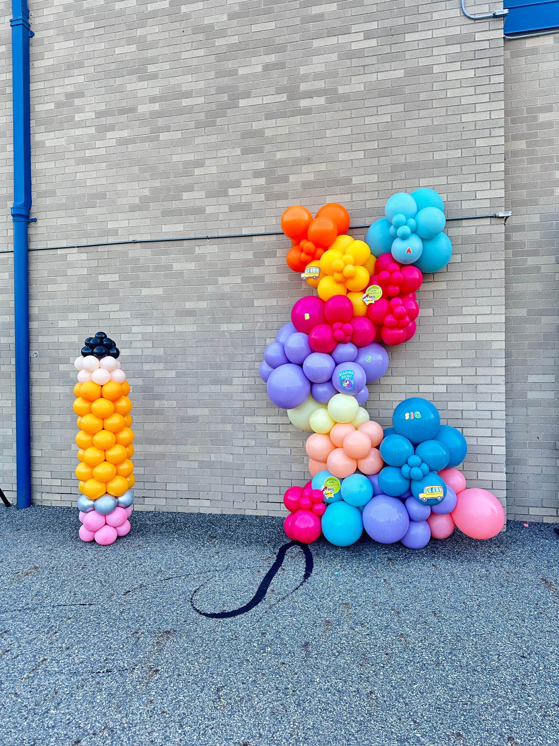 A bunch of colorful balloons are lined up against a brick wall