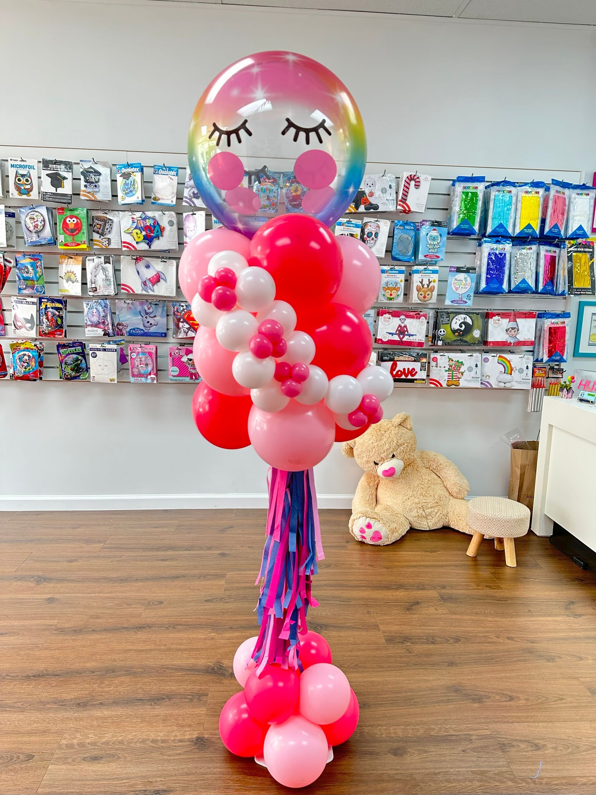 A bunch of balloons are sitting on a wooden floor in a room.