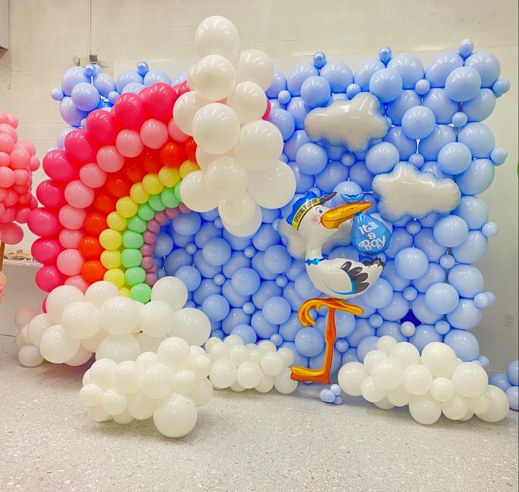 A wall of balloons with a stork and a rainbow