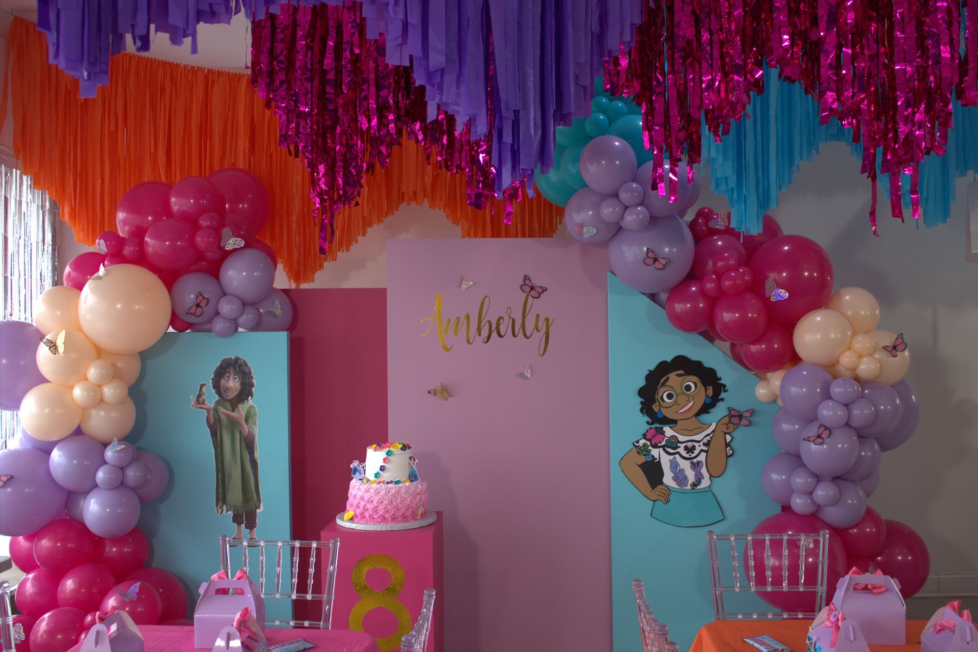 A room decorated with balloons and streamers for a girl 's birthday party.