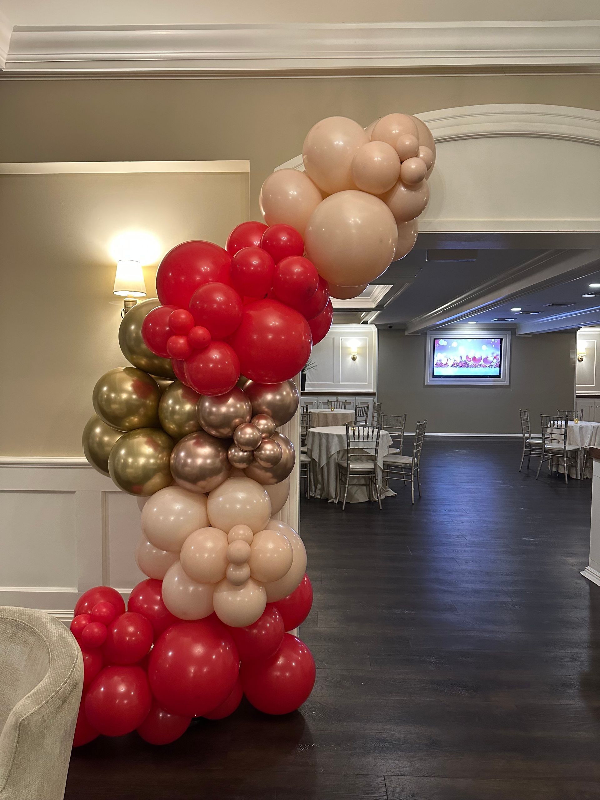 A woman in a red dress is sitting on a couch in front of a tent decorated with balloons.
