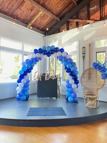 A room filled with blue and white balloon arch and a chair.