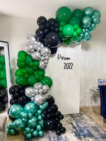 A room filled with green , black , and silver balloons.