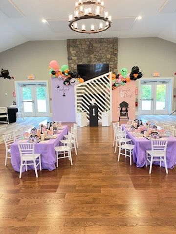A large room with tables and chairs set up for a birthday party.