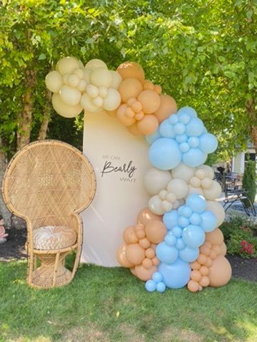 A wicker chair is sitting in front of a balloon arch.