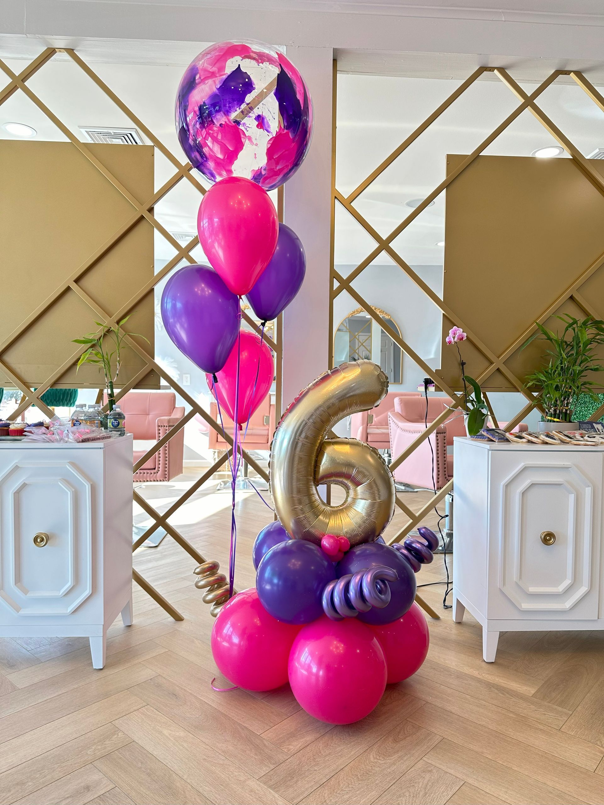 A bunch of pink and purple balloons with a number 6 on top
