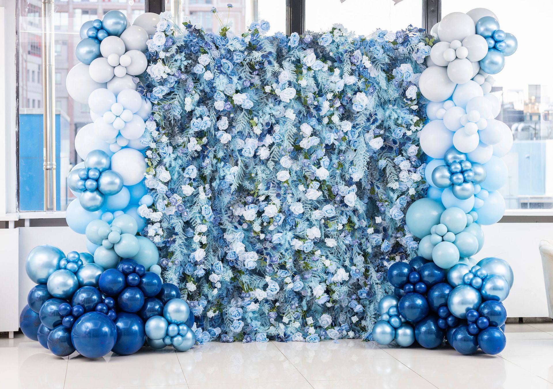 A wall of blue and white balloons and flowers.