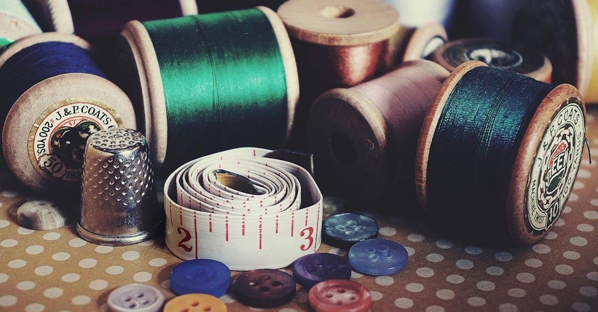 A table topped with spools of thread , buttons , a thimble and a measuring tape.