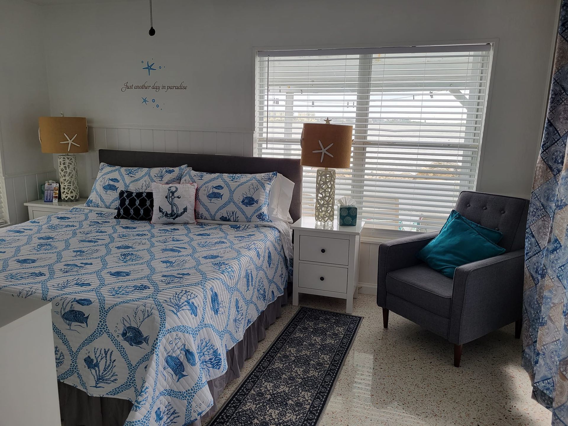 A bedroom with a king size bed , chair , nightstand and window.