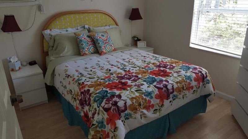 A bedroom with a bed , two nightstands , and a window.