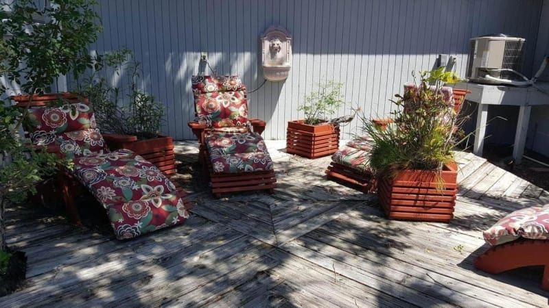 A wooden deck with chairs and potted plants on it.