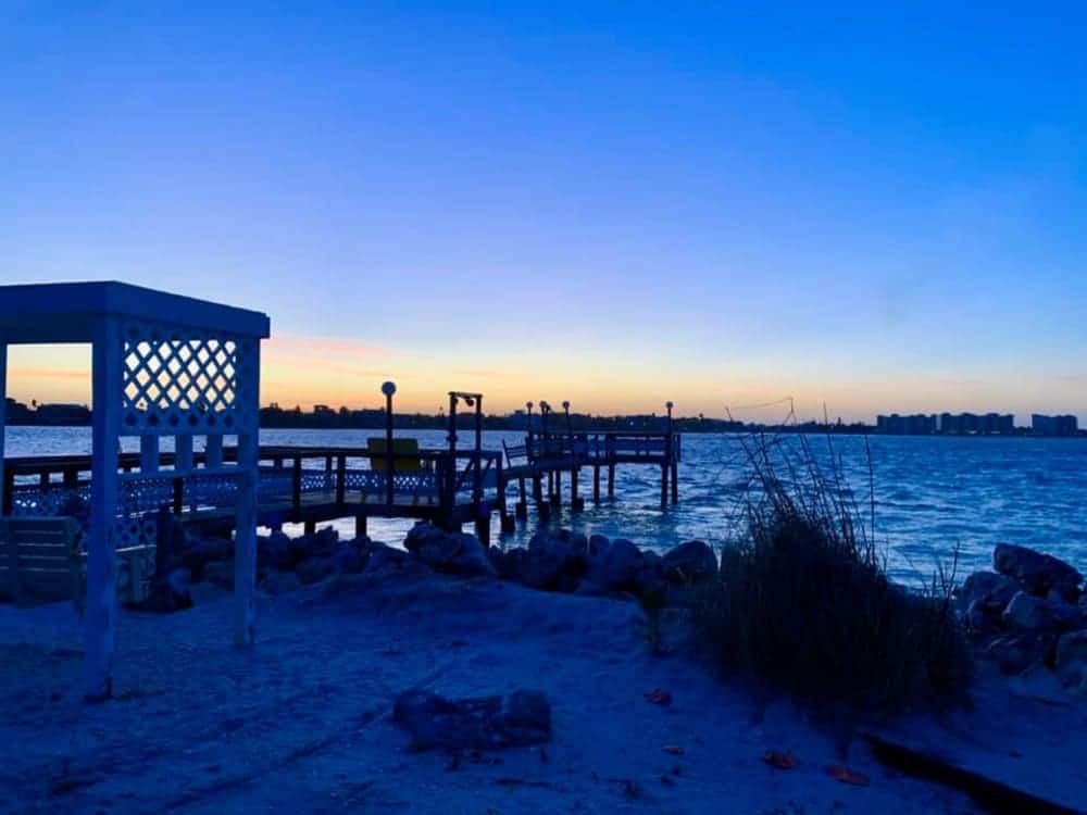 A sunset over a body of water with a gazebo in the foreground