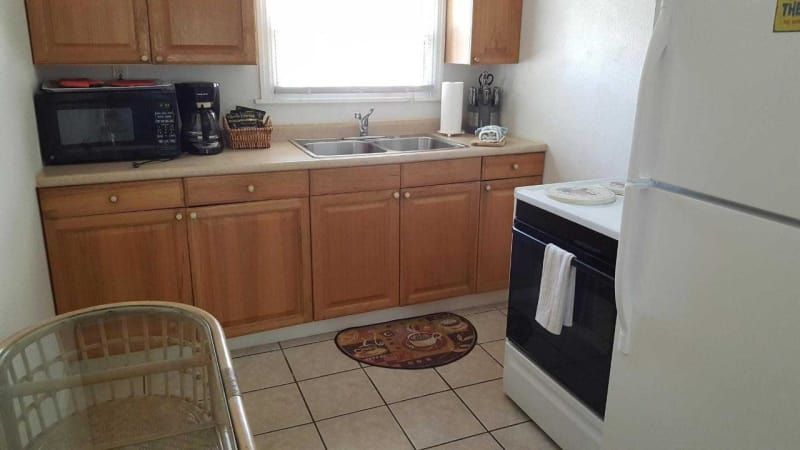 A kitchen with a sink , stove , microwave and refrigerator.