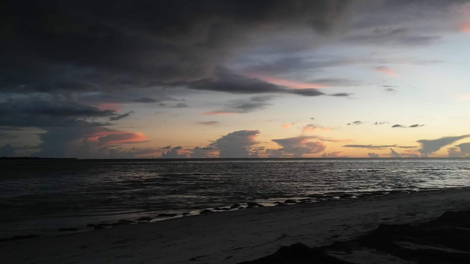 A sunset over a body of water with clouds in the sky