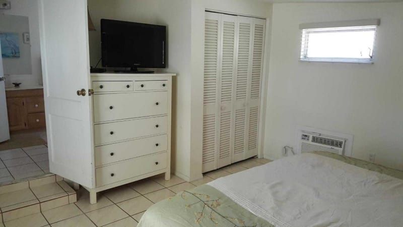 A bedroom with a bed , dresser , television and closet.