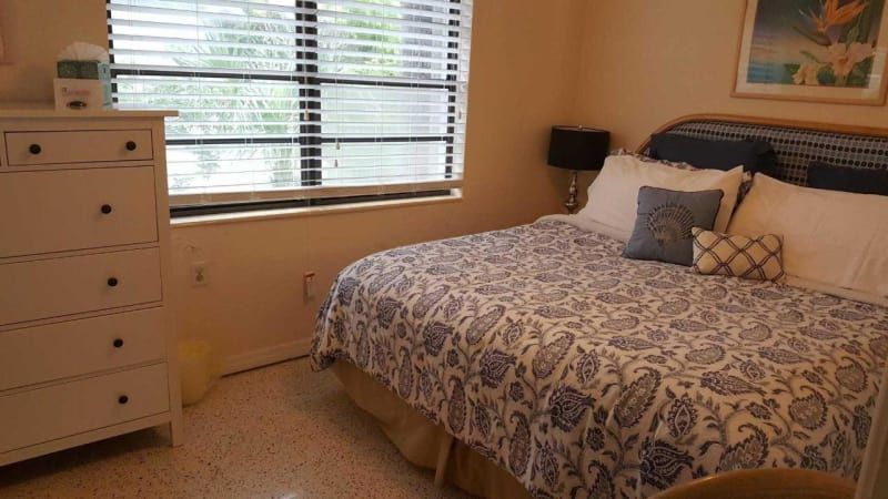 A bedroom with a bed , dresser , and window.