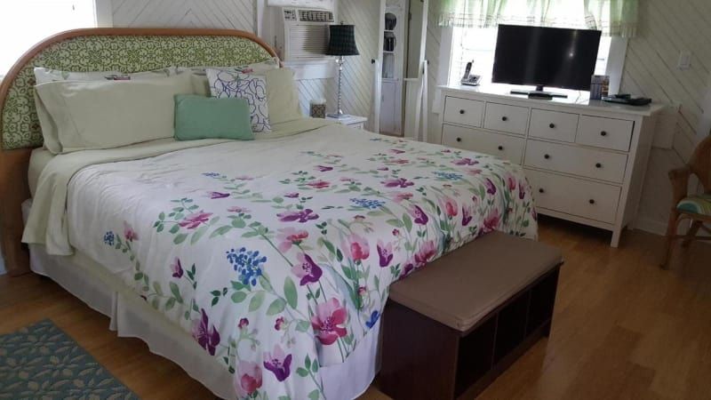 A bedroom with a large bed a dresser and a television