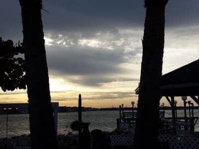 A sunset over a body of water with a gazebo in the foreground.