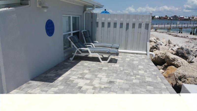 A patio with chairs and a fence leading to the beach