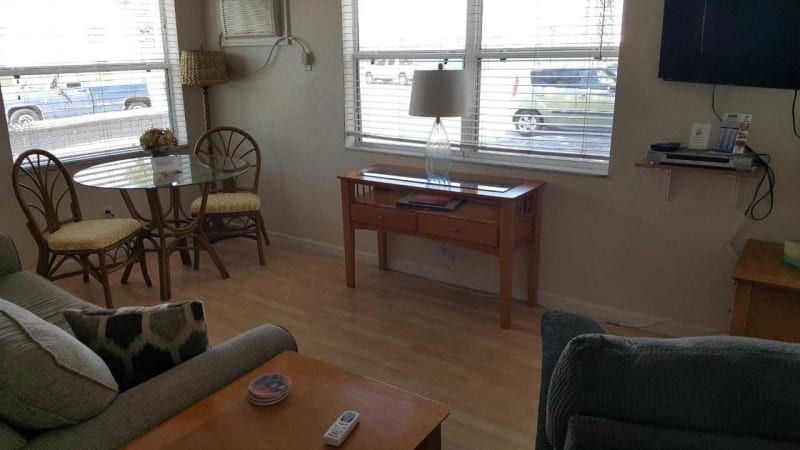 A living room with a couch , table , chairs and a flat screen tv.